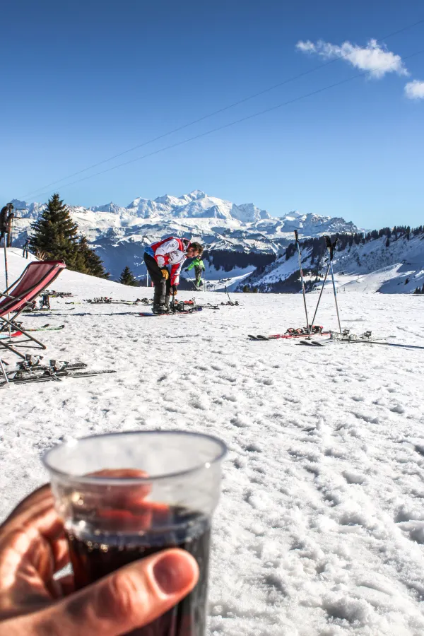 Un verre au premier plan devant des montagnes enneigées