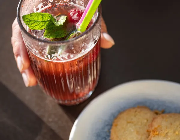 boisson te,ue dans la main et gateau salée dans une assiette gros plan