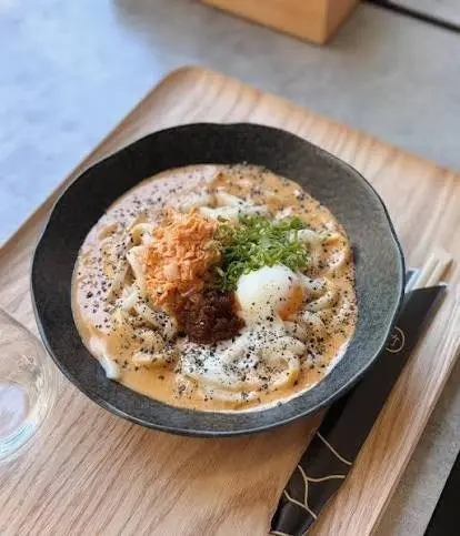 Nouilles udon servies dans un bouillon crémeux légèrement épicé, accom