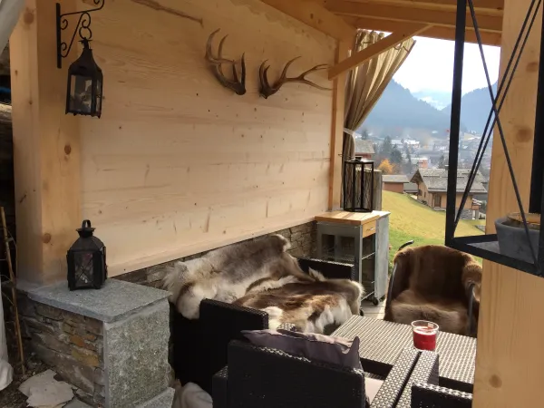 Coin détente extérieur abrité avec canapé et fauteuils, vue sur le village