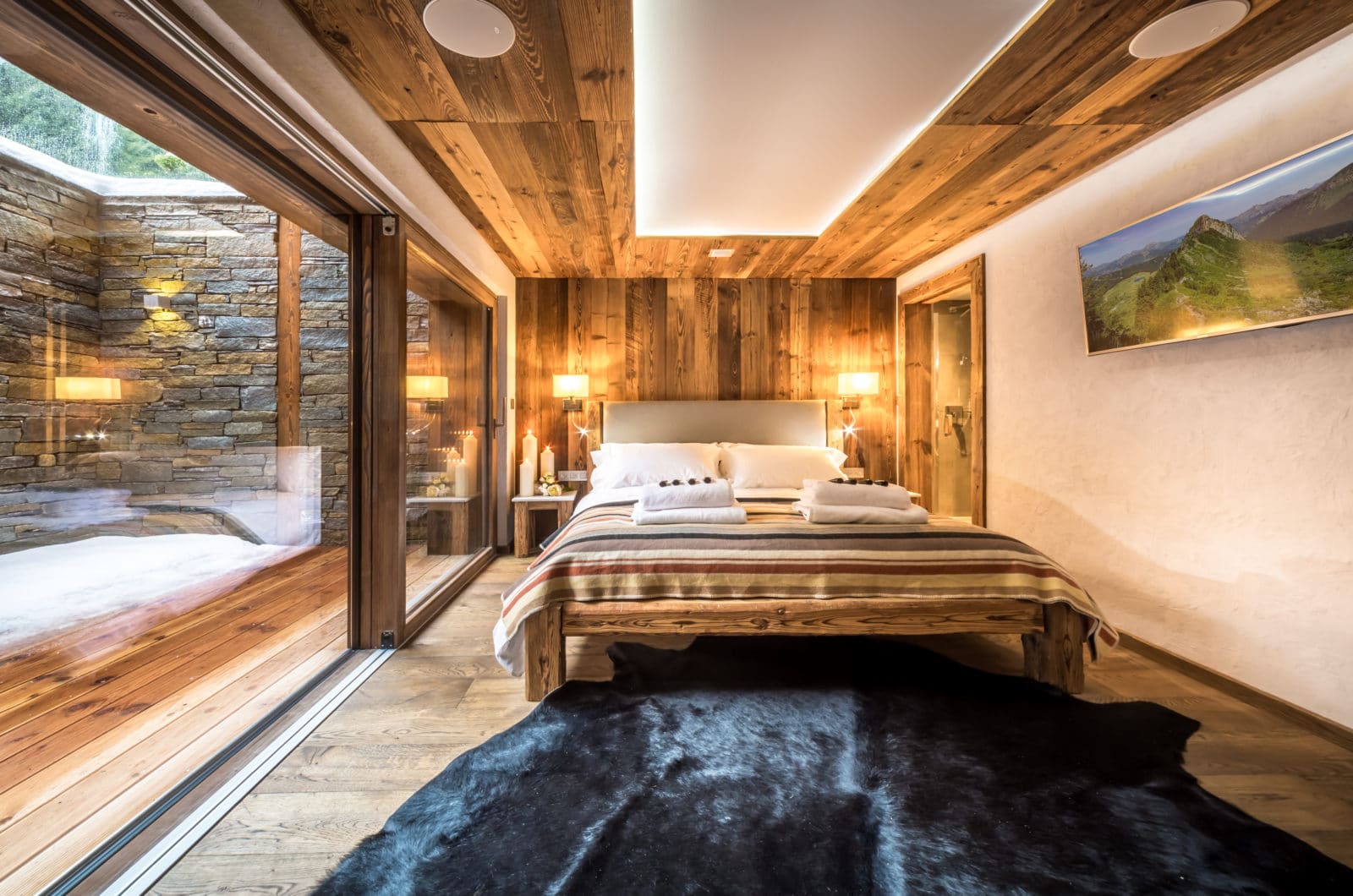 Chambre parentale avec salle de bains privé plus acces à un balcon privé, graande tete de lit en bois avec du rangement inclus, plafond en bois avec enceinte sonore encastrées.
