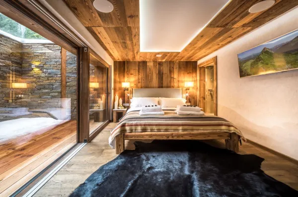 Chambre parentale avec salle de bains privé plus acces à un balcon privé, graande tete de lit en bois avec du rangement inclus, plafond en bois avec enceinte sonore encastrées.