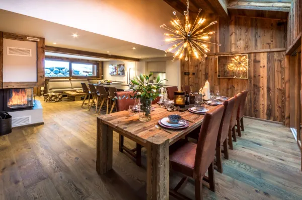 Salle à manger avec belle hauteur sous plafond, grande table en bois ouvert sur le salon avec la chaminée au centre le tout dans une ambiance chalet chic et cosy