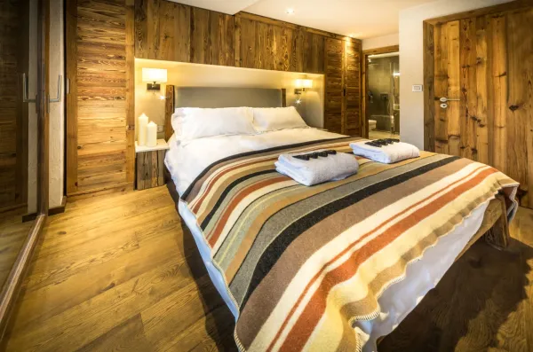 Chambre parentale avec salle de bains privé plus acces à un balcon privé, graande tete de lit en bois avec du rangement inclus, plafond en bois avec enceinte sonore encastrées.